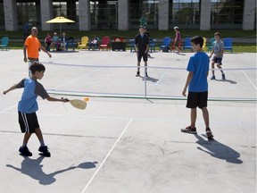 Zachary Kranabetter, 11, and brother Matthew Kranabetter, 15, in blue and Tristan Turner, 13, and brother Aidan, 15, Turner in black play pickleball on the Rink of Dreams at Ottawa City Hall on July 29.