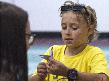 Seven-year-old Joshua with guide Marcelina Lassak (glasses) who leads the Spy Camp Kids at the Diefenbunker in Carp in folding paper cranes in an Origami class to send to Japan. They hope is to make between 600 and 1,000 cranes.