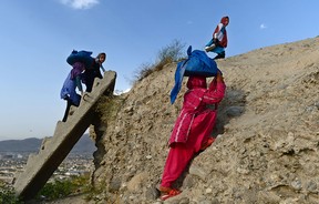 fghan children who work as street vendors climb a hilltop as they carry 'bolanis' (fried bread stuffed with potatoes) on their heads in Kabul on August 2, 2014.