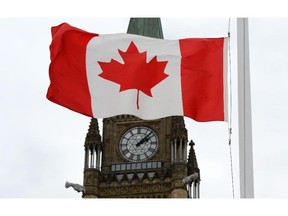 A Canadian flag blows in front of the Peace Tower on Parliament Hill.