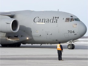 A ground crew member directs a Canadian C17 Globemaster as it arrives carrying the last troops returning from Afghanistan, Tuesday, March 18, 2014 in Ottawa.