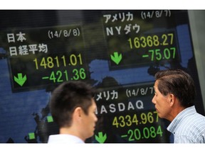 A man looks at an electronic stock board of a securities firm in Tokyo, Friday, Aug. 8, 2014.