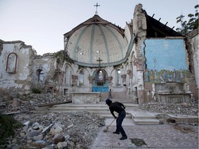 A man sweeps an exposed tiled area of the earthquake-damaged Santa Ana Catholic church, where he now lives, in Port-au-Prince, Haiti, Saturday, Jan. 12, 2013.