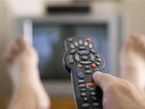 A man watches television and changes channels while relaxing.