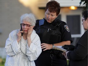 A police officer attempts to comfort a Bernice Schofield, the owner of a home that was completely destroyed in an overnight 2-alarm fire at 976 Arkell St. in Ottawa, Thursday, August 7, 2014.