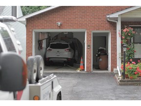 A tow truck prepares to pull a white Ford Escape that slammed into the garage of an Ancaster Avenue house Friday trapping two people inside the vehicle.