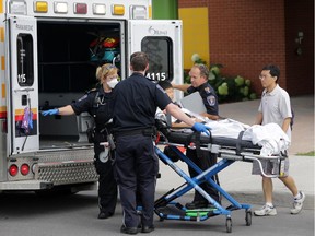 A young boy on a stretcher is wheeled into an ambulance by paramedics from St. Cecile Catholic School in Barrhaven (Ottawa), Thursday, July 31, 2014.