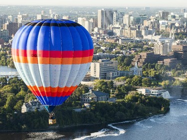 An aerial photograph taken from a hot air balloon shows a balloon floating over the Ottawa River with downtown Ottawa in the background Friday, August 29, 2014.