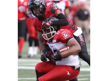 Brandyn Thompson #25 of the Ottawa Redblacks tackles Nik Lewis #82 of the Calgary Stampeders during a CFL match at TD Place in Ottawa on August 24, 2014.