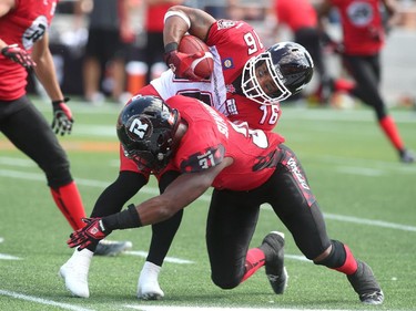 OTTAWA, ON - AUGUST 24: Jasper Simmons #31 of the Ottawa Redblacks tackles Marquay McDaniel #16 of the Calgary Stampeders during the second quarter of a CFL game at TD Place Stadium on August 24, 2014 in Ottawa, Ontario, Canada.
