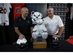 Carleton Ravens coach Steve Sumarah (L) and Ottawa Gee-Gees head coach Jamie Barresi exchanged a few friendly words and laughs at a press conference in the Carleton Ravens' locker room for the annual Panda Game at TD Place in Ottawa on Aug. 7, 2014. Kick-off is set for 1 p.m. on Saturday, Sept. 10, 2014. (David Kawai / Ottawa Citizen)