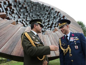 Colonel O.M. Calle Talledo (L) of Peru talks with fellow military attach�� Colonel Serkan Sevim of Turkey, both wearing a photo of Colonel Atilla Altikat, as members of the  diplomatic community mark the second anniversary of the inauguration of the Fallen Diplomats Memorial located at the corner of Island Park Drive and the Sir John A Macdonald Driveway.  Colonel Atilla Altikat of Turkey was gunned down at that location 32 years ago. Assignment #118115 Photo taken at 14:47 on August 27, 2014. (Wayne Cuddington/Ottawa Citizen)