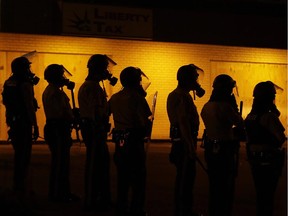 In this Aug. 17, 2014 file photo, police wait to advance after tear gas was used to disperse a crowd during a protest for Michael Brown, who was killed by a police officer in Ferguson, Mo.