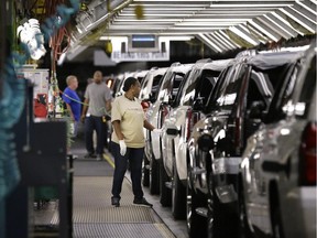 FILE - In this May 13, 2014 file photo, an auto worker inspects finished SUVs coming off the assembly line at the General Motors auto plant in Arlington, Texas.