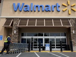 FILE - In this May 9, 2013 file photo, a worker pushes shopping carts in front of a Walmart store in La Habra, Calif. Wal-Mart Stores Inc. is expected to report quarterly results on Thursday, May 15, 2014.