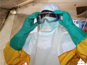 A file photo taken on June 28, 2014 shows a member of Doctors Without Borders (MSF) putting on protective gear at the isolation ward of the Donka Hospital in Conakry, where people infected with the Ebola virus are being treated. Guinea announced on August 9, 2014 it was closing its land borders with Liberia, Sierra Leone over Ebola fears.