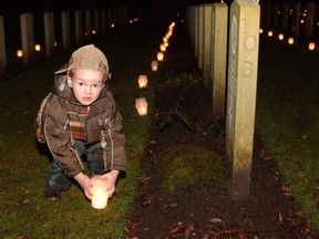 A schoolboy lights a candle on the grave of a Canadian soldier buried in the Holten Canadian War Cemetery. The candle-lighting ceremony is a Christmas Eve tradition in the Dutch town of Holten.