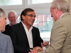 From left, Graham Bird welcomes guest Greg Kane in from the pouring rain at a reception Bird hosted on Thursday, August 21, 2014, as co-chair of The Ottawa Hospital Foundation's upcoming fundraising breakfast. (Caroline Phillips / Ottawa Citizen)