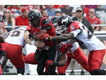 Ottawa's Jamill Smith is surrounded by Calgary's Tim St. Pierre (35, left), Karl McCartney (45) and Alvin Bowen (23, right) during a CFL game at TD Place in Ottawa on August 24, 2014.
