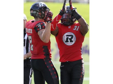 Jasper Simmons #31 of the Ottawa Redblacks celebrates with team mate Eric Fraser #7 following a tackle during a CFL match against the Calgary Stampeders at TD Place in Ottawa on August 24, 2014.