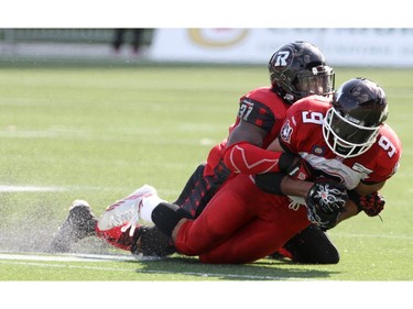 The Ottawa Redblacks' Jasper Simmons wraps up Jon Cornish of the Calgary Stampeders during a CFL game at TD Place in Ottawa on August 24, 2014.