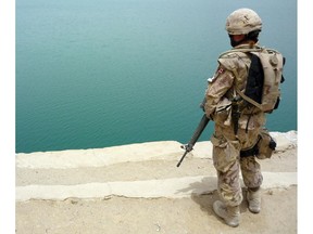 In this file photo, overlooking a splash of turquoise waters in an otherwise scorched desert landscape, a Canadian soldier stands on guard June 11, 2008.