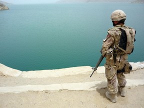 File photo: Overlooking a splash of turquoise waters in an otherwise scorched desert landscape, a Canadian soldier stands on guard June 11, 2008 as Canadian officials tour the Dahla Dam to inspect the site of Canada's "signature" aid project for Afghanistan.