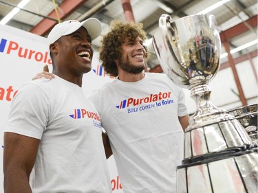 (L-R) The Ottawa  Redblacks QB, Henry Burris and Fury FC forward, Tom Heinemann smiles for the camera as they sort through the donated foods at the Ottawa Food Bank for Purolator Tackle Hunger weekend on Thursday, Aug. 14, 2014. Fans attending the Redblacks and Fury FC games in Aug. 15 and 17 are encouraged to bring non-perishable food items or cash donations to the volunteers stationed at the stadium gates. Fans will have the opportunity to have a photo taken with the Grey Cup and North American Soccer League (NASL) Soccer Bowl trophy.