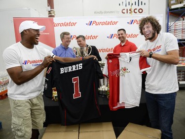(L-R) The Redblacks QB, Henry Burris and Fury FC forward, Tom Heinemann shows off the signed jerseys being donated to the Ottawa Food Bank for Purolator Tackle Hunger weekend on Thursday, Aug. 14, 2014.  Fans attending the Redblacks and Fury FC games in Aug. 15 and 17 are encouraged to bring non-perishable food items or cash donations to the volunteers stationed at the stadium gates. Fans will have the opportunity to have a photo taken with the Grey Cup and North American Soccer League (NASL) Soccer Bowl trophy.