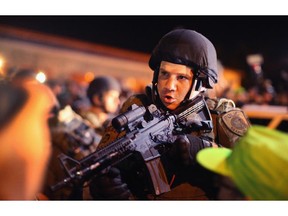 Police charge into the media work area with rifles at ready as they try to control demonstrators protesting the killing of teenager Michael Brown on August 19, 2014 in Ferguson, Missouri. Brown was shot and killed by a Ferguson police officer on August 9. Despite the Brown family's continued call for peaceful demonstrations, violent protests have erupted nearly every night in Ferguson since his death.