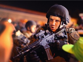 Police charge into the media work area with rifles at ready as they try to control demonstrators protesting the killing of teenager Michael Brown on August 19, 2014 in Ferguson, Missouri. Brown was shot and killed by a Ferguson police officer on August 9. Despite the Brown family's continued call for peaceful demonstrations, violent protests have erupted nearly every night in Ferguson since his death.