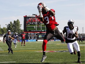 Jeff Fuller #31 of the Calgary Stampeders catches a pass for a touchdown in front of Reggie Jones #20 of the Ottawa REDBLACKS in the first half of their CFL football game August 9, 2014 at McMahon Stadium in Calgary, Alberta.