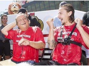 Ottawa Senators' team owner, Eugene Melnyk, seated left, and defenceman Erik Karlsson, seated right, react after being doused with ice water by teammates for the ALS ice bucket challenge at Canadian Tire Centre Tuesday, August 19, 2014.