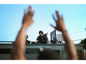 FERGUSON, MO - AUGUST 13:  Police stand watch as demonstrators protest the shooting death of teenager Michael Brown on August 13, 2014 in Ferguson, Missouri. Brown was shot and killed by a Ferguson police officer on Saturday. Ferguson, a St. Louis suburb, is experiencing its fourth day of violent protests since the killing.