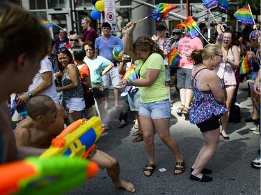 Participants in the Capital Pride parade spray water at the crowd as they march on Bank Street last month.