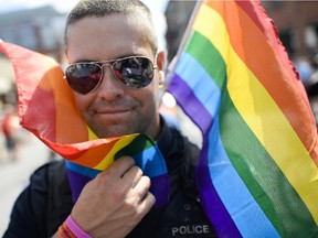 A police officer at the 2014 Capital Pride Parade smiles at the camera as they march on Bank Street.
