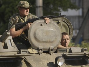 Pro-Russian rebels ride on an APC in the town of Krasnodon, eastern Ukraine, Sunday, Aug. 17, 2014. A column of several dozen heavy vehicles, including tanks and at least one rocket launcher, rolled through rebel-held territory on Sunday.