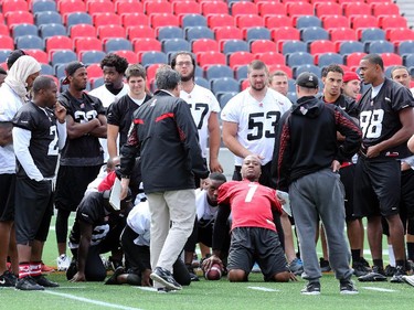 QB Henry Burris (centre) stretches out during the post-practice talk from Head Coach Rick Campbell.