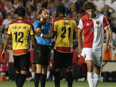 Referee Marie-Soleil Beaudoin gestures to Darnell King #21 of the Fort Lauderdale Strikers as Tom Heinemann #9 of the Ottawa Fury walks away during an NASL match at TD Place in Ottawa on August 9, 2014.