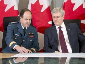 Canadian Prime Minister Stephen Harper looks over a map with the Chief of Defence Staff General Thomas Lawson before announcing Canada will send six CF-18 fighter jets to the eastern Europe as part of a NATO mission during a press conference in Ottawa on Thursday, April 17, 2014. Canada will send six CF-18 jet fighters to Poland as part of a beefed-up NATO force formed in response to the crisis in Ukraine.
