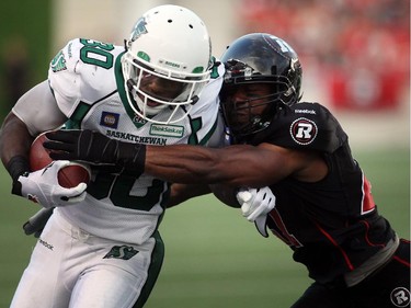 TJ Hill of the Ottawa Redblacks grabs onto Will Ford of the Saskatchewan Roughriders during the first half of CFL game action at TD Place in Ottawa on Saturday, Aug. 2, 2014. (Cole Burston/Ottawa Citizen)