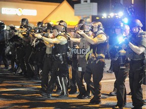 Law enforcement officers watch on during a protest on West Florissant Avenue in Ferguson, Missouri on August 18, 2014. Police fired tear gas in another night of unrest in a Missouri town where a white police officer shot and killed an unarmed black teenager, just hours after President Barack Obama called for calm.