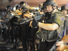 Law enforcement officers watch on during a protest on West Florissant Avenue in Ferguson, Missouri on August 18, 2014. Police fired tear gas in another night of unrest in a Missouri town where a white police officer shot and killed an unarmed black teenager, just hours after President Barack Obama called for calm.