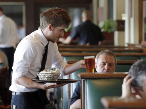 A waiter serves a customer. What's better — tipping or paying a living wage.