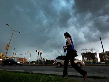 A woman hurries to the bus shelter as storm clouds and severe weather threaten commuters and pedestrians along Merivale Rd. Photo taken at 15:58 on September 5, 2014.