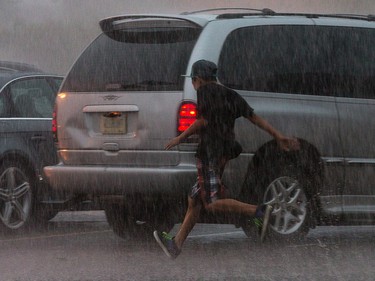 A youngster runs to his car as storm clouds and severe weather threaten commuters and pedestrians along Merivale Rd. Photo taken at 15:58 on September 5, 2014.