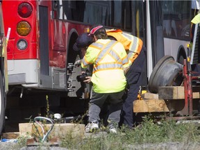 TSB (Transportation Safety Board) investigator examines the hub of the bus involved in bus-train accident at Woodroffe and the VIA train crossing near Fallowfield.