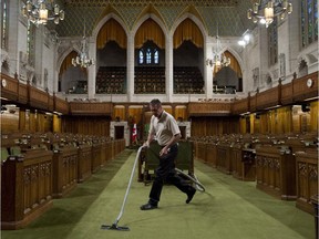 A House of Commons worker vacuums the carpet as the chamber is prepared for the resumption of the session on Parliament Hill.