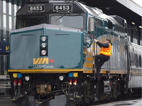 A Via Rail employee climbs aboard a locomotive at the train station in Ottawa on Monday, December 3, 2012.