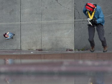 A woman looks up as Ottawa Citizen editor Blair Crawford hangs off the rope as as participants rappel from the top of the Morguard Building at 280 Slater Street in the 5th annual Drop Zone Ottawa event which raises money for Easter Seals. September 22, 2014.